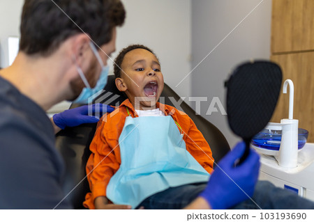 Dark-skinned boy looking in the mirror at dentists office Dark-skinned boy looking in the mirror at dentists office 103193690