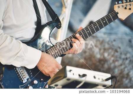 Close-up of a professional man's hands playing the fretboard of an electric blues strat type guitar 103194068