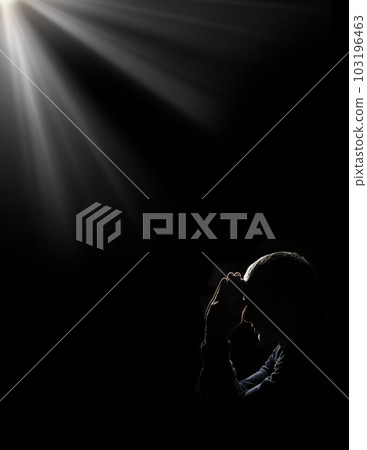 Young man praying on dark background Young man praying on dark background 103196463