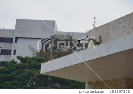 One white active cctv, which is stuck on the wall in the yard 103197358