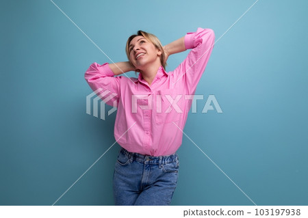 pretty young blond european woman model wearing pink shirt and jeans and feeling confident against 103197938