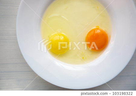 Raw eggs in a white plate. Yolks of different colors Raw eggs in a white plate. Yolks of different colors 103198322