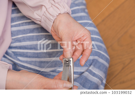 [Middle-aged woman cutting her fingernails flooring] 103199032