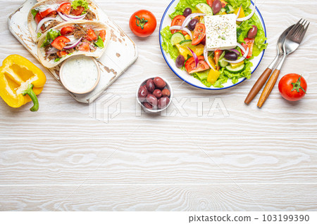 Traditional Greek Food: Greek Salad, Gyros with meat and vegetables, Tzatziki sauce, Olives on White rustic wooden table background from above. Cuisine of Greece. Space for text Traditional Greek Food: Greek Salad, Gyros with meat and vegetables, Tzatziki sauce, Olives on White rustic wooden table background from above. Cuisine of Greece. Space for text 103199390