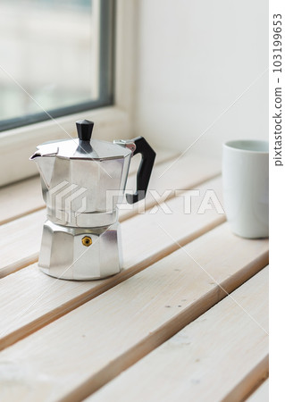 Moka pot and coffee cup on windowsill - drinks and breakfast concept Moka pot and coffee cup on windowsill - drinks and breakfast concept 103199653
