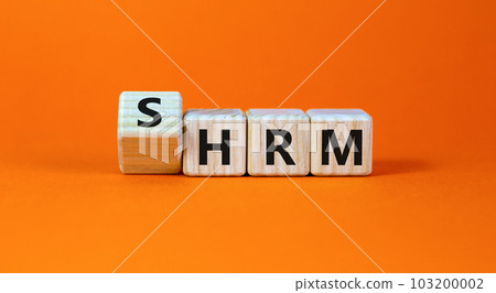 SHRM strategic human resource management HRM symbol. Words SHRM, strategic human resource management on cubes on a beautiful orange background. Businessman hand. Business SHRM HRM concept. Copy space. 103200002