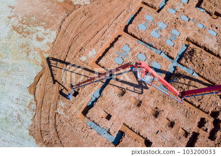 Contractor worker pours concrete into house foundation using concrete pump Contractor worker pours concrete into house foundation using concrete pump 103200033