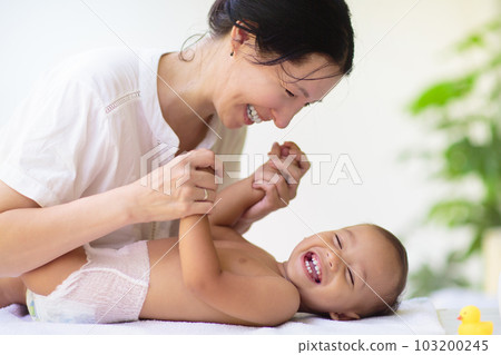 Mother changing diaper on newborn baby. Mother changing diaper on newborn baby. 103200245