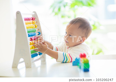 Baby boy playing with wooden abacus. 103200247