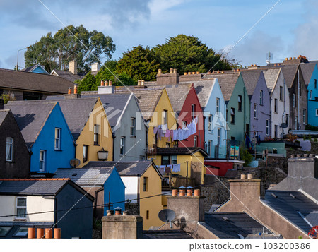 Multicolored European houses, street of the small Irish town of Cobh, urban landscape. Blue sky over the city. Houses under blue sky Multicolored European houses, street of the small Irish town of Cobh, urban landscape. Blue sky over the city. Houses under blue sky 103200386