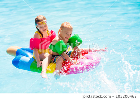 Kids on inflatable float in swimming pool. Kids on inflatable float in swimming pool. 103200462
