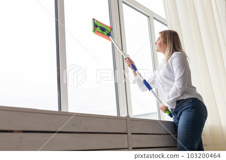 Happy woman cleaning window with sponge mop at home - housework and housekeeping concept Happy woman cleaning window with sponge mop at home - housework and housekeeping concept 103200464