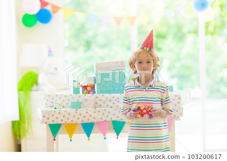 Kids birthday party. Child opening present. 103200617