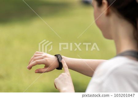 Young woman checks her smart watch. Close up of hand with device. The concept of a modern device and wellness Young woman checks her smart watch. Close up of hand with device. The concept of a modern device and wellness 103201047