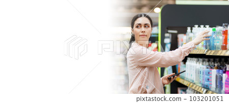 Web banner of shopping. Portrait of Caucasian pretty young woman holds cellphone and choosing products in supermarket. Mock up with copy space. Concept of consumerism Web banner of shopping. Portrait of Caucasian pretty young woman holds cellphone and choosing products in supermarket. Mock up with copy space. Concept of consumerism 103201051