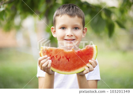 Cute boy eating watermelon outdoors in summer. Healthy eating seasonal fruits 103201349