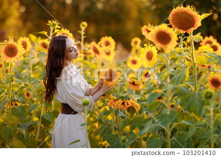 Beautiful woman in a dress in a field of sunflowers 103201410