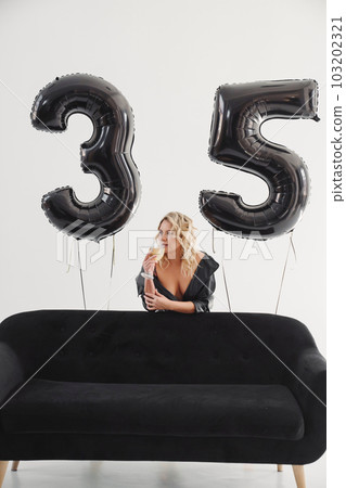 a naked blonde with tattoos in a black coat by a black sofa. birthday a naked blonde with tattoos in a black coat by a black sofa. birthday 103202321