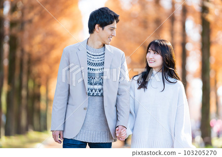 年輕夫婦手牽手走在綠樹成蔭的街道上 103205270