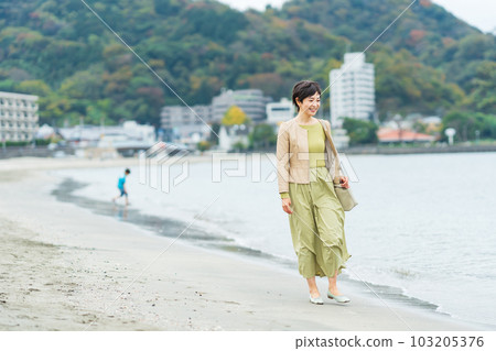 Middle-aged woman walking on the beach 103205376