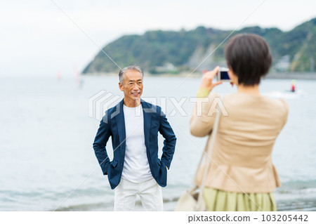 A middle-aged couple taking pictures at the beach 103205442