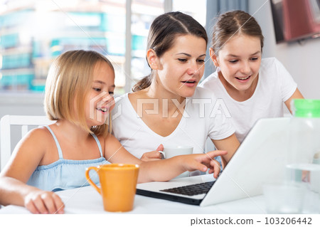 Enthusiastic sisters watch something interesting with their mom on laptop Enthusiastic sisters watch something interesting with their mom on laptop 103206442