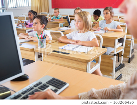Diligent tweens studying in classroom with female teacher 103206450