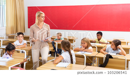 Teacher tells an interesting lecture in free communication with students elementary school in classroom Teacher tells an interesting lecture in free communication with students elementary school in classroom 103206541