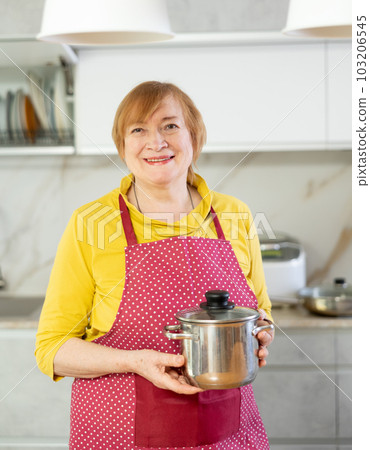 Adult woman in apron posing with saucepan 103206545
