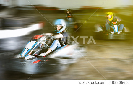 Group of people driving go-carts at racing track 103206603