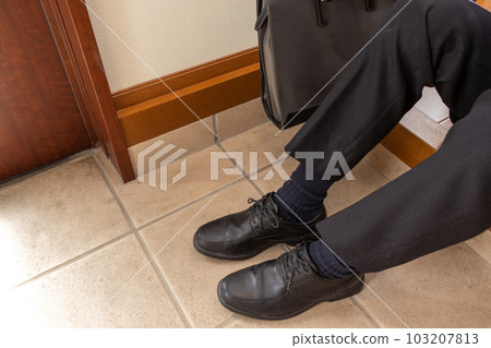 A man sitting with his shoes on at the entrance 103207813