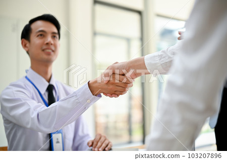 A professional Asian male office worker shaking hands with his colleague 103207896