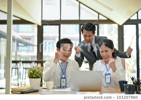 Overjoyed Asian businesspeople are looking at a laptop screen, celebrating their project's success. 103207960
