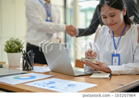 A young Asian female assistant taking notes on her spiral notepad during the meeting. A young Asian female assistant taking notes on her spiral notepad during the meeting. 103207964