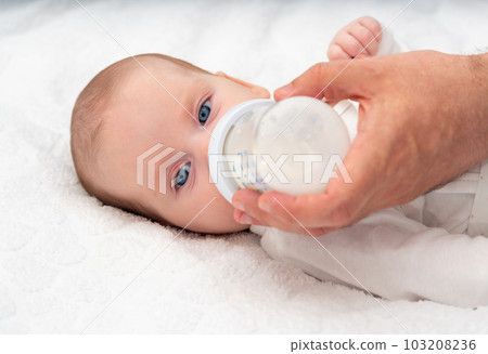 Beautiful baby eats formula from a bottle supported by his father Beautiful baby eats formula from a bottle supported by his father 103208236