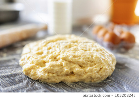 Top view of dough, rolling pin and baking ingredients on a dark wooden table 103208245