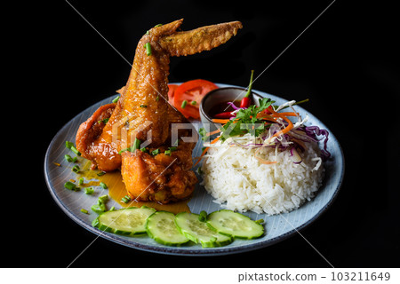 Roasted chicken wing in Vietnamese style with rice, vegetables and sauce isolated on black background side view 103211649