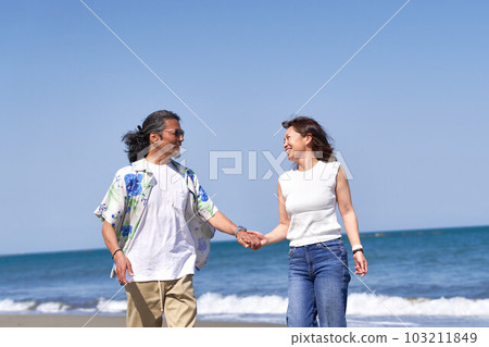 Middle senior couple walking hand in hand on the beach Middle senior couple walking hand in hand on the beach 103211849