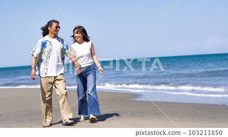 Middle senior couple walking hand in hand on the beach Middle senior couple walking hand in hand on the beach 103211850