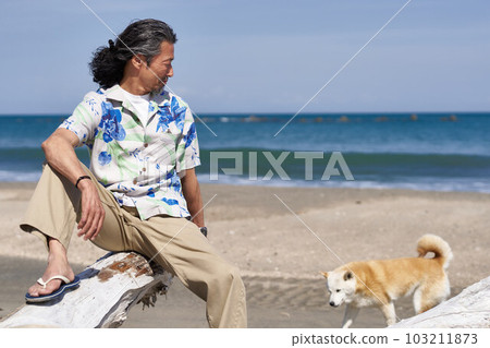 中年男子在沙灘上玩狗 103211873