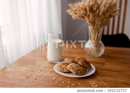 delicious freshly baked oatmeal cookies with chocolate on a wooden background with a glass of milk or yogurt. High quality photo 103212757