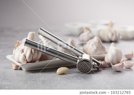 Garlic and garlic press on a grey table. 103212765
