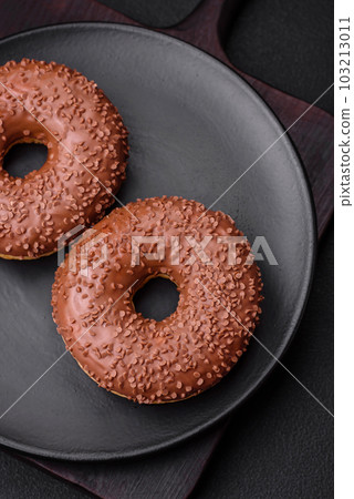 Delicious chocolate glazed donut sprinkled with chocolate chips Delicious chocolate glazed donut sprinkled with chocolate chips 103213011