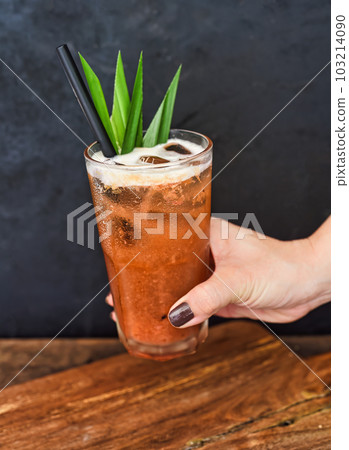 Hand holding iced tropical tea made of green tea and orange jam on wooden table background Hand holding iced tropical tea made of green tea and orange jam on wooden table background 103214090