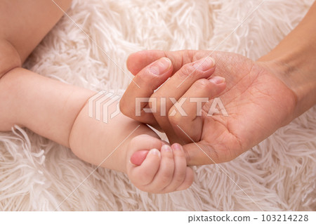 A baby's hand holding a finger A baby's hand holding a finger 103214228