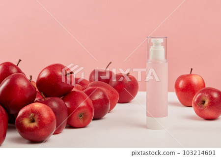 Minimal mockup background for product presentation with pink bottle unlabeled placed on pink background and surround by ripe red apples. Advertising scene for cosmetic of apple extract 103214601