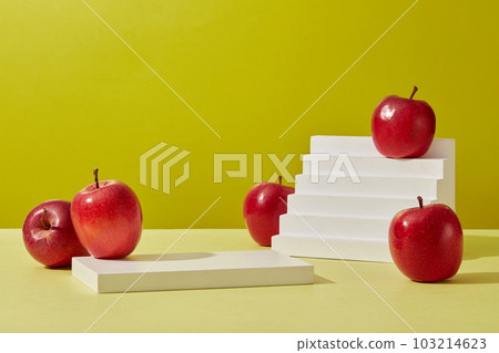 Product and promotion concept for advertising cosmetic product of apple extract. Some ripe red apples decorated on a green background with rectangle white podium and white stairway. Front view 103214623