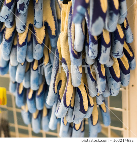 Rubberized grey work gloves hanging on the wall. Part of work-wear and protection equipment. 103214682