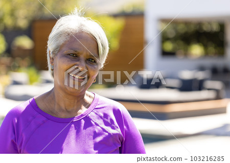 Portrait of happy senior biracial woman looking at camera and smiling in sunny garden, copy space Portrait of happy senior biracial woman looking at camera and smiling in sunny garden, copy space 103216285