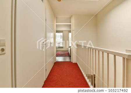 a long hallway with red carpet on the floor and an open door leading to another room that is white in color a long hallway with red carpet on the floor and an open door leading to another room that is white in color 103217492